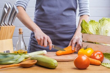 The hands of a woman cook prepare a salad with fresh vegetables. Healthy food. White background