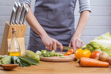 The hands of a woman cook prepare a salad with fresh vegetables. Healthy food. White background