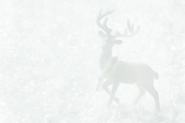 White deer standing in snow forest. Magic winter scene. Christmas New Year greeting card poster banner in monochrome. Minimalist creative image in scandinavian style. Copy space for text.