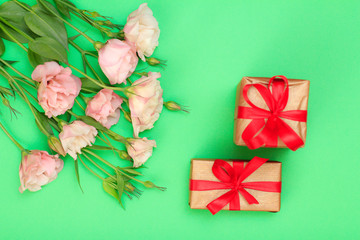 Pink flowers with leaves and two gift boxes on green background