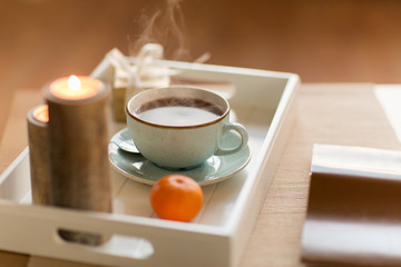 holidays and still life concept - cup of hot chocolate, christmas gift, mandarin and candles on table