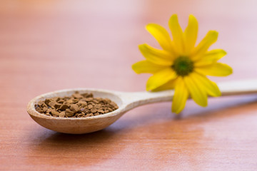 Wooden spoon with coffee and yellow flower on the table