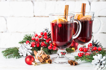 Mulled wine in glass mug with fruit and spices on white.