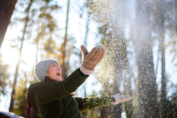 Girl enjoys winter, frosty day, snow. playing with snow, a woman throws white, loose snow into the...