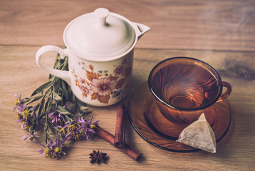 Cup of hot tea on wooden autumn background with flowers and Cinnamon Sticks.Top view. Warm drink concept.
