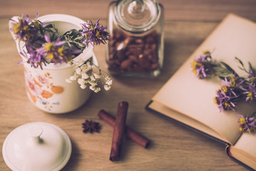 Warm autumn concept. Cinnamon Sticks, flowers, book, glasses and tea on wooden background.
