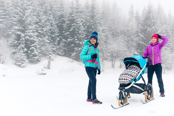Happy family in mountains. Mother with baby stroller enjoying motherhood in winter forest