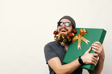 Cheerful young bearded man holding a big gift for christmas