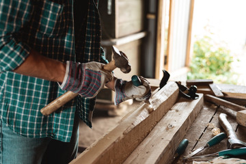 Carpenter with a hammer and chisel handles wood. Joiner at work in the workshop