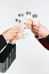 People hold glasses of champagne with champagne in their hands on a white background, a close-up