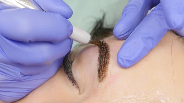 close-up hands of the master doing brows tattoo. permanent eyebrow makeup. 4K