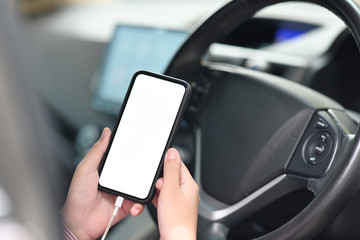Cropped shot of female hand holding mobile phone in car.