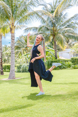 girl with pigtails in a black dress and sunglasses is having fun between the palm trees