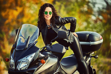 Fototapeta na wymiar Young woman resting sitting on a motorcycle . Travel and tourism concept