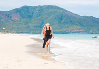 Fototapeta na wymiar beautiful girl in a black dress walks on the beach
