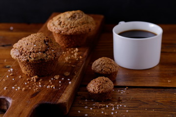 Ready to eat Bran muffins and coffee on a wooden board