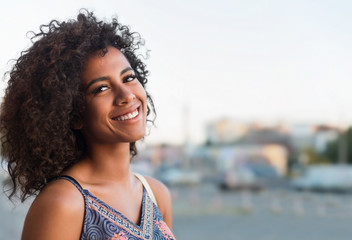Black woman with curly hair flying in wind enjoying evening