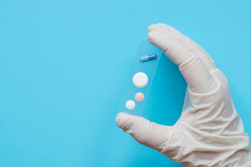 hand in medical glove holding pills, test delivery, laboratory research, treatment concept