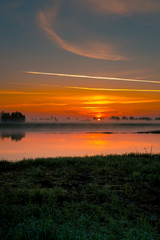 Fototapeta na wymiar Dawn over a small river on a foggy morning
