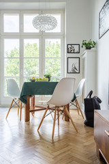 White wooden chairs around kitchen table in modern apartment, real photo
