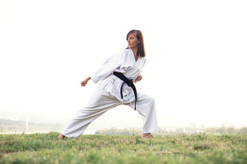 A young karate professional practicing while wearing a black belt.