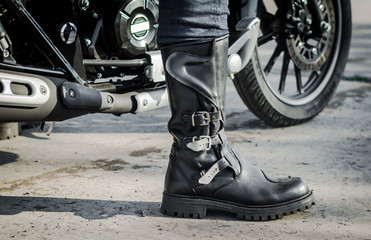 Fototapeta na wymiar biker leg in a boot against the backdrop of a motorcycle
