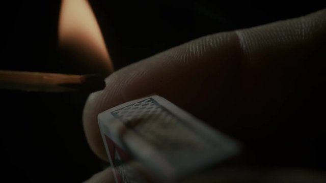 Burning match close-up over black background.