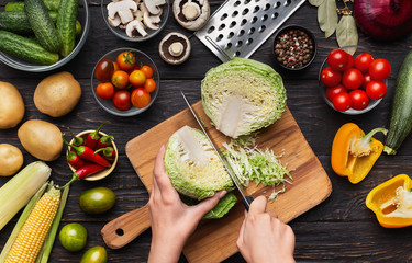 Female hands chopping savoy cabbage on wooden board