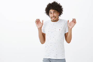 Intense guy feeling discomfort waiting for punishment. Portrait of displeased nervous cute hispanic guy in t-shirt raising palms in surrender and squinting, apologizing for making mistake