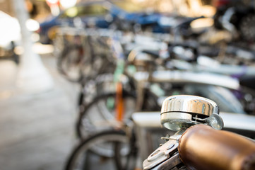closeup of a bicycle handle bar and bell on an unfocused background of a bicycle parking in the center of the city.