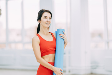 Portrait of a beautiful girl in the gym. Yoga style and instructor with Mat.