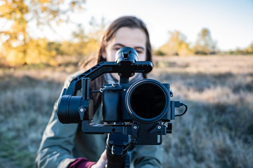 Female videographer holding a gimbal with mirrorless camera. Woman with stabilized camera rig...