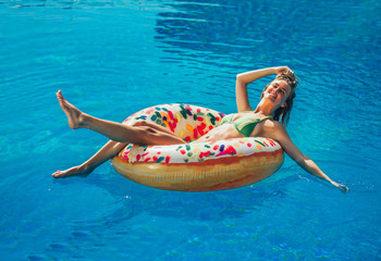 Summer Vacation. Enjoying suntan Woman in bikini on the inflatable mattress in the swimming pool.