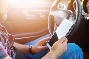 bearded man with a tablet in the car