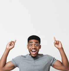 Excited african-american man pointing upwards at copy space - obrazy, fototapety, plakaty