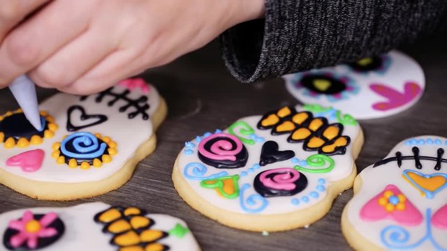 Step by step. Decorating sugar skull cookies with different color royal icing
