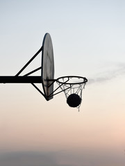Silhouette of a basketball hoop and backboard at sunset