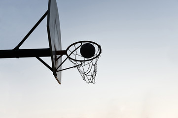 Silhouette of a basketball hoop and backboard at sunset