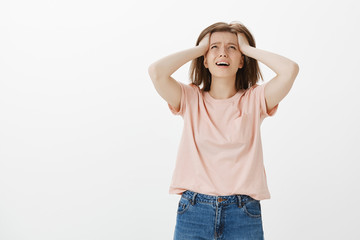 God why me. Portrait of miserable sad caucasian woman in casual outfit, whining and crying while looking up, holding hands on hair and frowning, being stuck in terrible situation with no way out