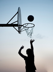 Silhouette of a young girl shooting a basketball 
