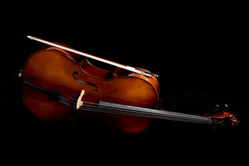  Close up of a cello and a bow set against a black background