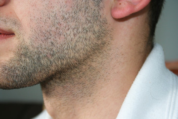 A man's face with a slight beard. A few days beard on the guy's chin. Macro picture taken from the...