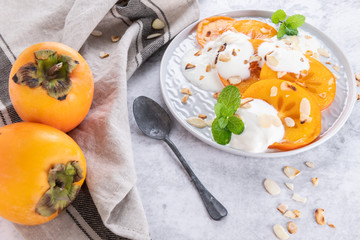 Sliced persimmon with yogurt and almonds.