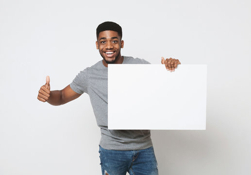 African-american man holding white blank board and showing thumb up