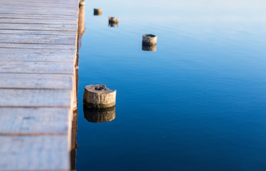 Wooden pier and pegs sticking out of the water on a blue lake
