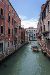 Fototapeta na wymiar Rotes Boot fährt durch Venedig Kanal 