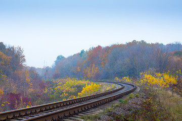 Fototapeta na wymiar The railway track among colorful trees in the fall_