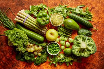 Fresh, natural, green vegetables, fruits and herbs assortment placed on a rusty metal background. Top view.