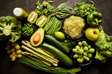 Green healthy food composition with avocado, broccoli, apple smoothie cucomber asparagus kiwi bean. Placed on dark background. Top view.
