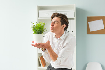 Fun, business and people concept - handsome man blowing at plant in his office, joke, the 1st of april